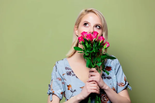 Красивая блондинка в платье с розами на зеленом фоне — стоковое фото