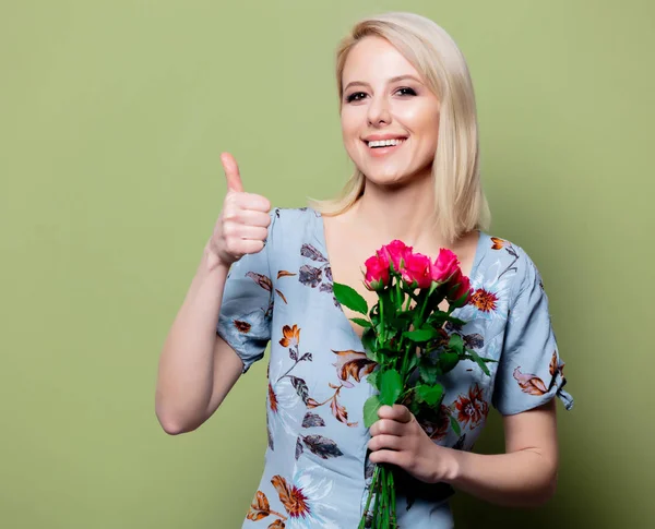 Krásná blondýna v šatech s růžemi na zeleném pozadí — Stock fotografie