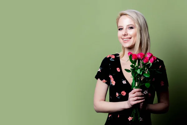 Mooie blonde vrouw in jurk met rozen op groene achtergrond — Stockfoto