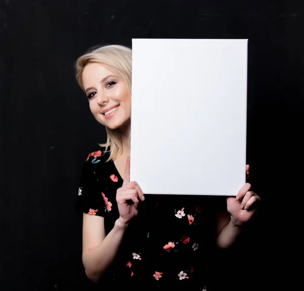 Blonde Frau mit weißem Brett auf dunklem Hintergrund — Stockfoto