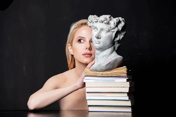 Blondýna vedle starožitné busty muže na knihách — Stock fotografie