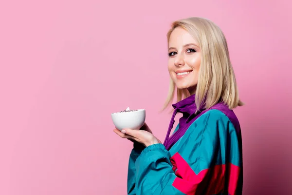 Mulher loira em terno esporte dos anos 90 com xícara de café no backgr rosa — Fotografia de Stock