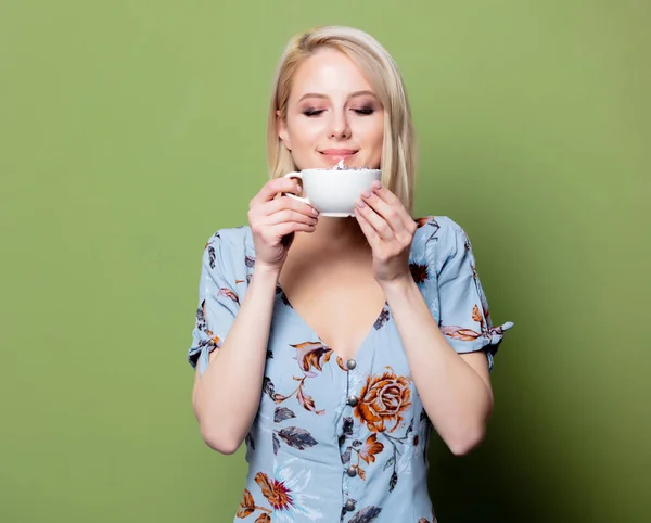 Blonde Frau im Kleid mit Tasse Kaffee auf grünem Hintergrund. St. — Stockfoto