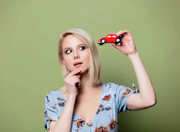Blonde Frau mit rotem Auto auf grünem Hintergrund — Stockfoto