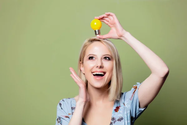 Blondýny žena wiith žlutý boulb na zeleném pozadí — Stock fotografie