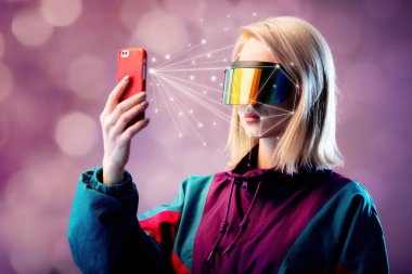 VR gözlüklü sarışın yüz tarama algoritmasıyla cep telefonu tutuyor.