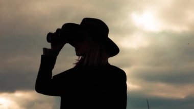 Kırsalda dürbünü olan tarz bir kadın.