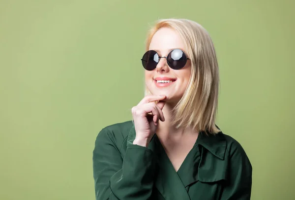 Blond Vrouw Mantel Ronde Zonnebril Groene Achtergrond — Stockfoto