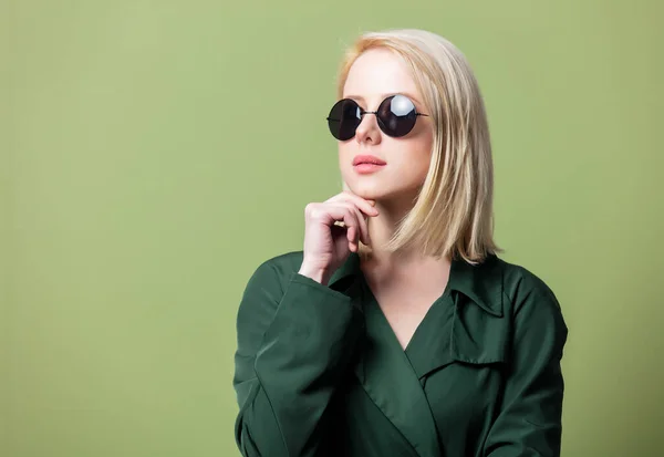 Blond Vrouw Mantel Ronde Zonnebril Groene Achtergrond — Stockfoto