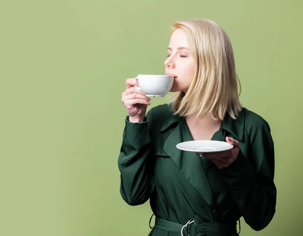 Блондинка Плаще Чашкой Кофе Зеленом Фоне — стоковое фото