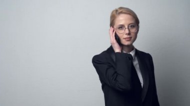 Klasik takım elbiseli bir iş kadını cep telefonuyla konuşuyor.