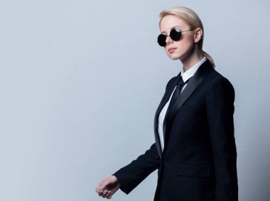 Klasik siyah takım elbiseli ve güneş gözlüklü bir iş kadını.