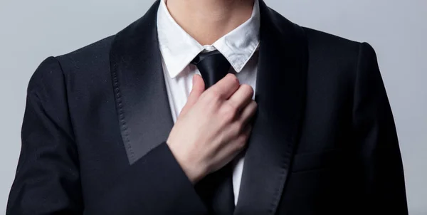 ビジネスの女性はグレーの背景で黒いネクタイを調整し — ストック写真