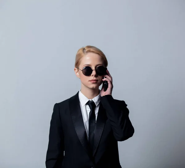 穿着经典黑色西装戴着太阳镜在手机上聊天的时尚女商人 — 图库照片