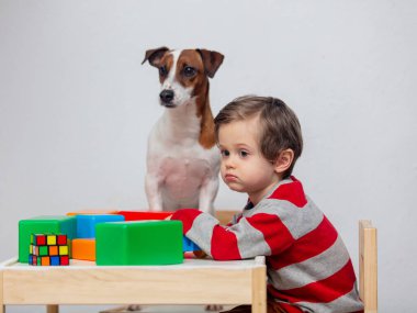 Küçük çocuk bir köpekle masada oynuyor. 