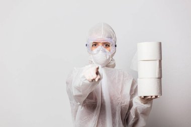 Koruyucu takım elbiseli genç bir doktor ve beyaz arka planda tuvalet kağıdı olan maskeli gözlükler.