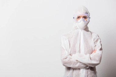 Koruyucu giysili genç bir doktor ve beyaz arka planda maskeli gözlükler.