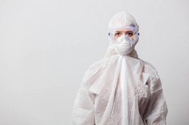 Koruyucu giysili genç bir doktor ve beyaz arka planda maskeli gözlükler.