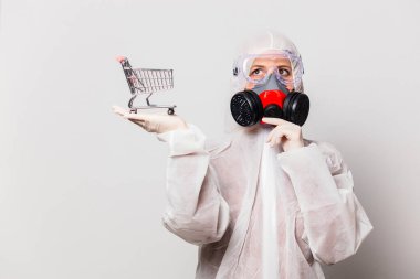 Koruyucu giysili kadın ve maskeli gözlüklü kadın alışveriş arabası tutuyor.