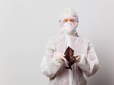 Koruyucu giysili kadın doktor ve maskeli gözlüklü kadın cüzdanı boş.