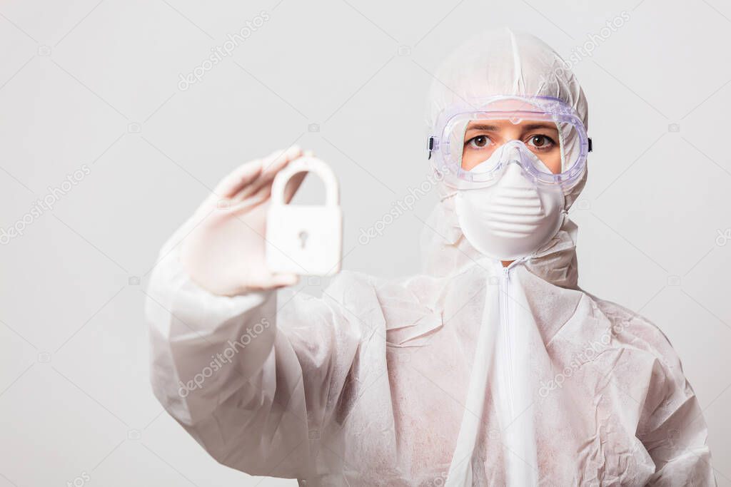 female doctor in protection suit and glasses with mask holds lock