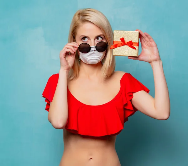 Blonde Frau Bikini Und Gesichtsmaske Mit Geschenkbox Auf Blauem Hintergrund — Stockfoto