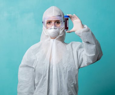 Koruma giysilerindeki doktor COVID-19 aşısını tutuyor.