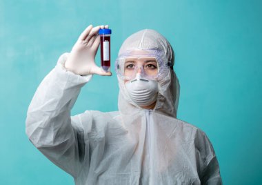 Koruma giysilerindeki doktor COVID-19 aşısını tutuyor.