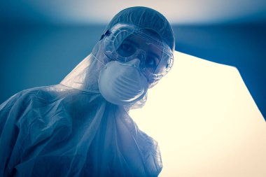 Laboratuvarda koruyucu giysiler ve arka planda ışık olan bir doktor. 