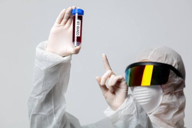 Koruma giysilerindeki doktor COVID-19 aşısını tutuyor.