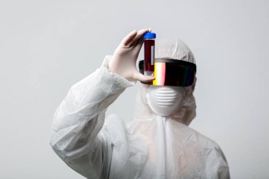 Koruma giysilerindeki doktor COVID-19 aşısını tutuyor.