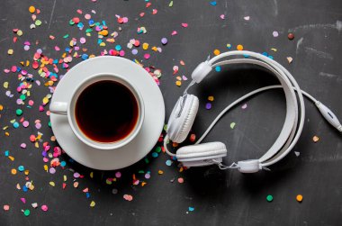 Masada konfeti olan bir fincan kahve ve kulaklık.