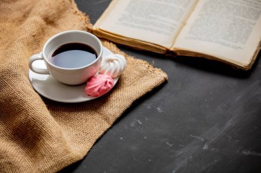 Bir fincan kahve, krema ve eskimiş bir kitap.