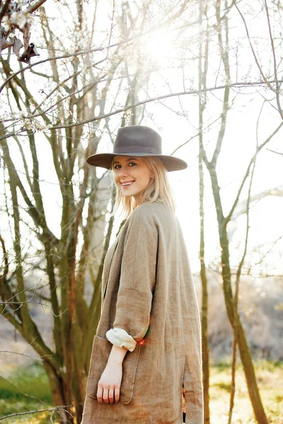 サンセットの桜の庭で帽子を被ったスタイリッシュな女の子 — ストック写真