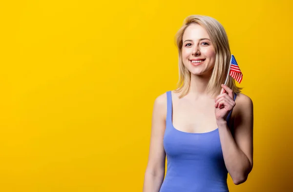 美丽的金发女人 黄底上挂着美国国旗 — 图库照片