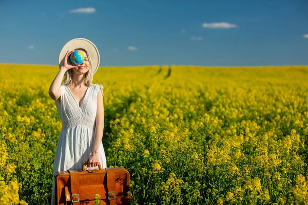 美しい女性のドレスでスーツケースと地球の世界で菜の花畑で春の時間 — ストック写真