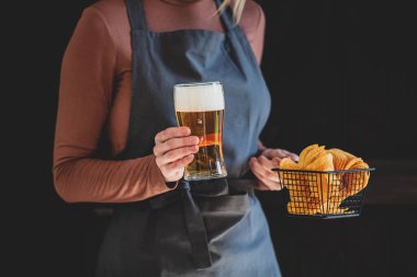 Kadın garson elinde bira ve patates kızartması tutuyor. 