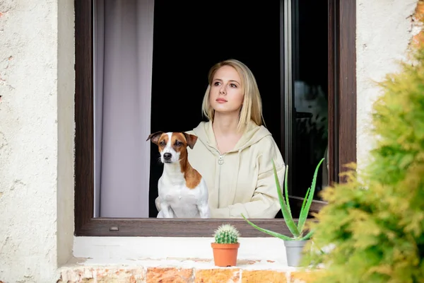 woman with a dog sits at the window during quarantine