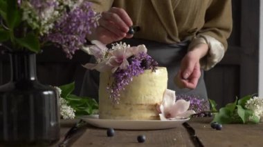 Masada leylak ve manolya çiçekleri ile süslenmiş beyaz düğün pastası.