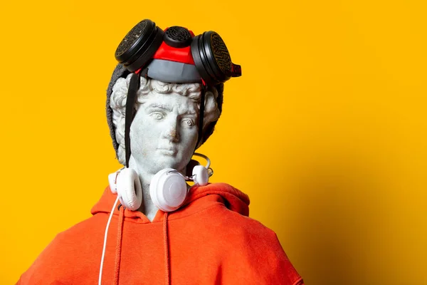 Teen Sculpture Orange Hoodie Face Mask Hat Headphones Yellow Background — Stock Photo, Image