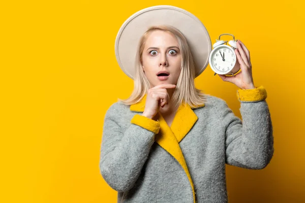 Style Femme Blonde Chapeau Manteau Avec Réveil Sur Fond Jaune — Photo