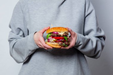 Kız el ele tutuşup beyaz arka planda bir burger yiyor.