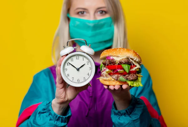 Blondes Mädchen Gesichtsmaske Mit Burger Und Wecker Auf Gelbem Hintergrund — Stockfoto