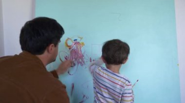 Baba ve oğul karantina sırasında duvarları boyarlar.