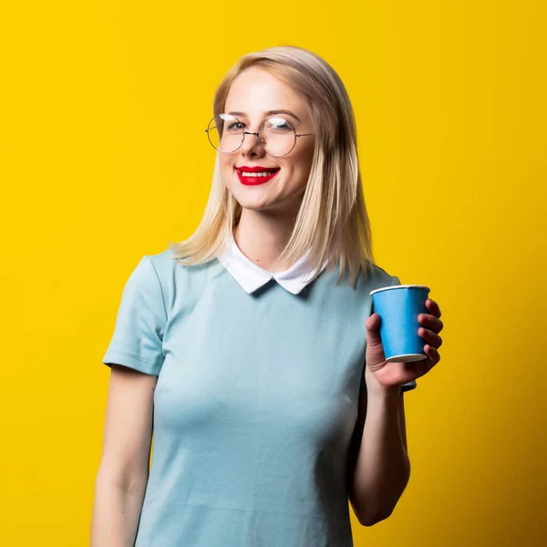 Blond Meisje Blauwe Jurk Bril Papieren Beker Gele Achtergrond — Stockfoto