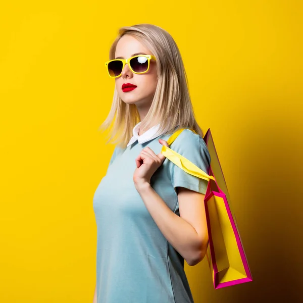 Ragazza Bionda Abito Blu Borse Della Spesa Sfondo Giallo — Foto Stock