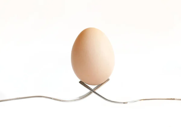 Пасхальне яйце тримається на столових приборах на білому тлі — стокове фото