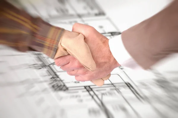 Worker and businessman shaking hands over house renovation plans — Stock Photo, Image