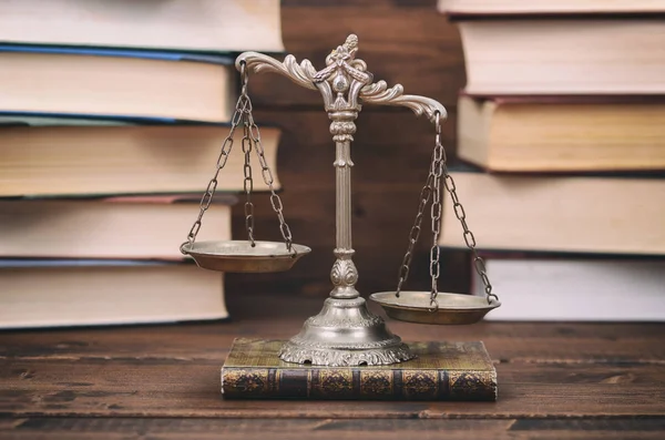 Maßstäbe der Justiz und Gesetzbücher auf einem hölzernen Hintergrund. — Stockfoto