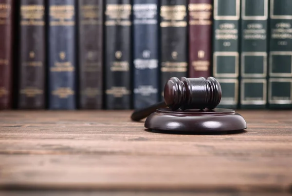 Σφυρί δικαστή σε μαύρο φόντο ξύλινη μπροστά από τη βιβλιοθήκη νόμου — Φωτογραφία Αρχείου